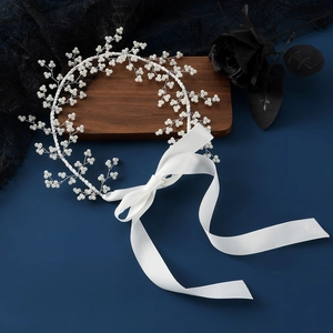 Elegant bridal hairband with handmade pearls and white satin ribbons on deep blue setup