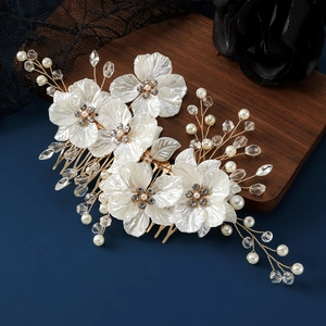 Macro detail of bridal hair comb with white shell petals, pearls, and crystals on gold wire