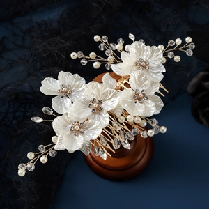 Elegant bridal hair comb with white shell petals, pearls, and crystals on a gold base