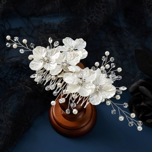 Detail of bridal hair comb with shell petals, pearls, and crystals on a wood stand