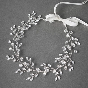 Elegant bridal hair vine with silver rhinestones and white satin ribbons on dark background