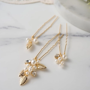 Detailed close-up of 3-piece golden bridal hair pins with pearls, leaves and rhinestones