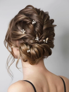 Detailed view of handmade pearl bridal hair pins and gold leaf clips on brown updo hairstyle