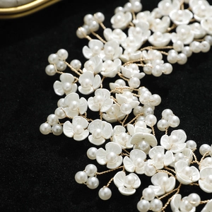Handmade bridal hair vine with white flowers and pearls on golden wire over black velvet