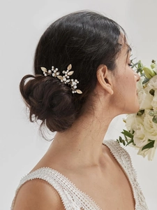 Elegant gold bridal hair comb with pearls and rhinestones on a low bun hairstyle