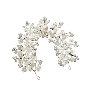 Handmade bridal headband with white ceramic flowers and pearls on a gold wire base