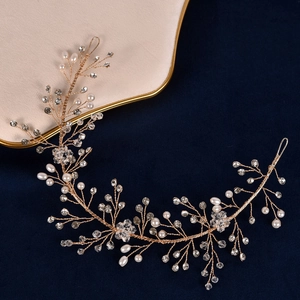 Close-up of handmade bridal headband with gold wires, white pearls and crystal flowers