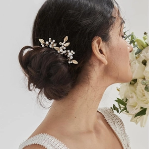 Golden bridal hair pin set with leaf design and white pearls on elegant low bun hairstyle