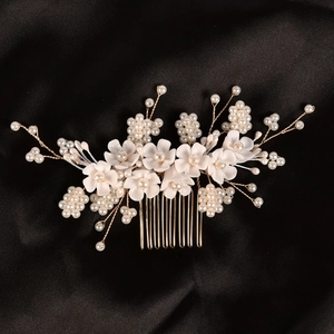 Dettaglio di fiori in resina bianca e perle su un pettine per capelli dorato da sposa