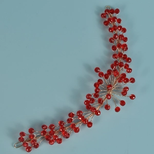 Dettaglio dell'archetto fatto a mano in filo dorato con perline di cristallo rosso sfaccettate