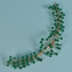 Dettaglio dell'accessorio per capelli da sposa con cristalli verdi e fili in oro