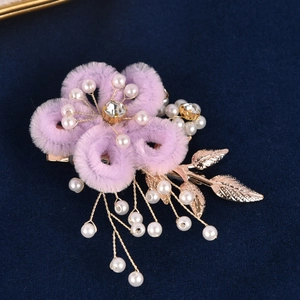 Détail d'une épingle à cheveux fleur en peluche violette avec perles et feuilles dorées