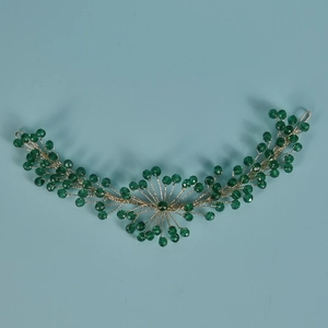 Dettaglio dell'accessorio per capelli da sposa in cristallo verde con filo dorato
