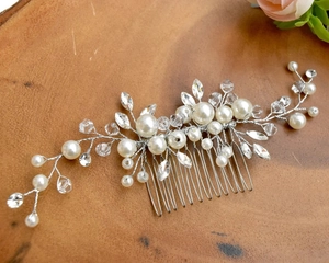 Detail of silver bridal hair comb with pearls and crystals on a wooden background