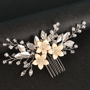 Detail of handmade bridal hair comb with cream flowers, silver leaves and crystal beads