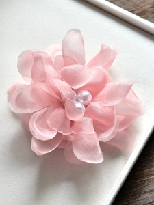 Détail d'une pince à cheveux fleur rose en mousseline avec pétales et trois perles nacrées