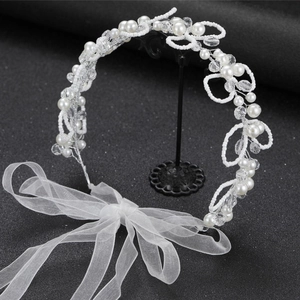 Elegant bridal hairband with white pearls and crystal beads on a dark background