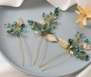 Detail of emerald and gold handmade bridal leaf hair pins with crystal beadwork