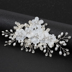 Détail de fleurs en tissu blanc avec perles et strass sur un peigne à cheveux de mariée