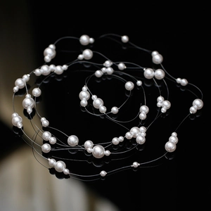 Elegant bridal hair vine with shimmering white pearls on a reflective black surface