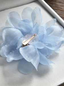 Détail de la pince à cheveux fleur en mousseline bleu clair avec clip en métal doré