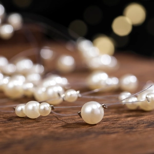 Elegant bridal hairband with assorted white pearls on a dark wooden background