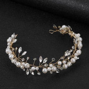 Close-up of handmade bridal headband with gold wires, white pearls and crystal details
