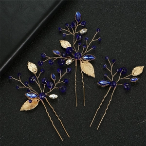 Detail of three-piece U-shaped hair pins with navy blue crystals and golden leaf motifs