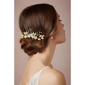 Détail du peigne à cheveux doré avec feuilles et perles sur une coiffure de mariée chic