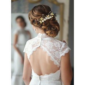 Détails de peignes à cheveux mariée dorés avec feuilles et perles sur un chignon élégant