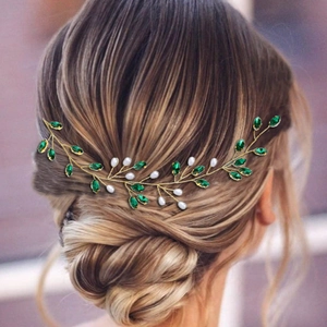 Dettaglio di tralcio per capelli da sposa con cristalli smeraldo e perle su chignon basso
