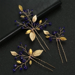 Detailed view of handmade gold leaf hair pins with deep blue beads for bridal hairstyles