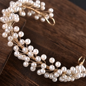 Macro detail of bridal hairband with white pearls and gold wire vine design