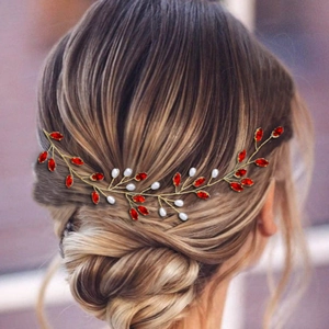 Dettaglio di tralcio per capelli da sposa con strass rossi e perle su filo dorato