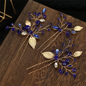 Detailed macro view of handmade gold leaf hair pins with deep blue crystal beads set