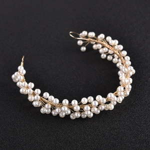 Close-up of flexible bridal hairpiece with white pearls and gold metal wire weaving