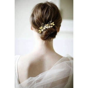 Détail du peigne à cheveux doré avec feuilles et perles sur une élégante coiffure de mariée