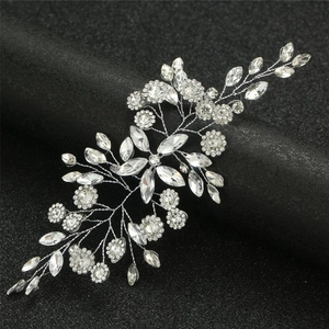Detail of silver bridal hairpiece with marquee rhinestones on a black textured stand