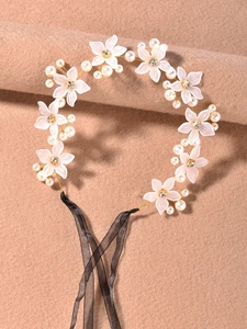Détail d'un bandeau floral fait main avec pétales blancs, perles et ruban en organza noir