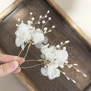 Close-up of handmade bridal hair pins with white gauze flowers and gold metal wire details