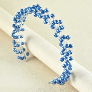Close-up of hand-woven bridal headband with blue pearls and silver wires on a display stand