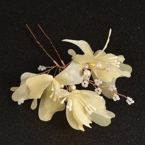 Detail of handcrafted bridal hair pin with silk yellow flowers and pearl stamens