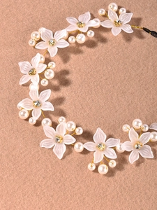 Détail d'une vigne à cheveux faite main avec fleurs de résine blanche et perles sur fil doré