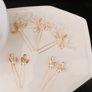 Handmade 7-piece bridal hair pin set with pearls and golden leaves on a white plate