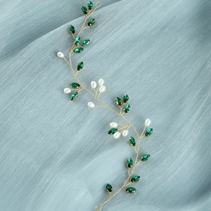 Dettaglio di accessorio per capelli da sposa con cristalli verdi e perle su filo d'oro