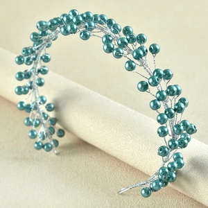 Detail of handcrafted teal pearl and silver wire bridal hairpiece on a display stand