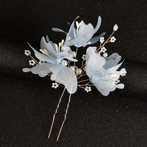 Detailed macro of handmade bridal hair fork with blue fabric petals and white pearls