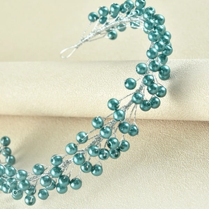 Close-up of handmade teal pearl headband with intricate silver wire weaving