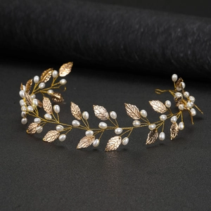 Detailed close-up of golden metal leaves and white pearls on bridal vine headband