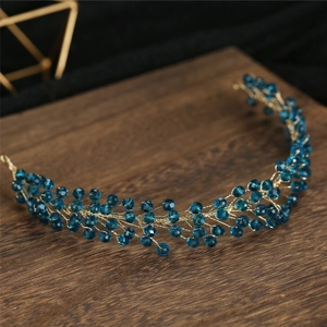 Detail of handcrafted gold wire bridal headband with faceted blue crystal beads on wood